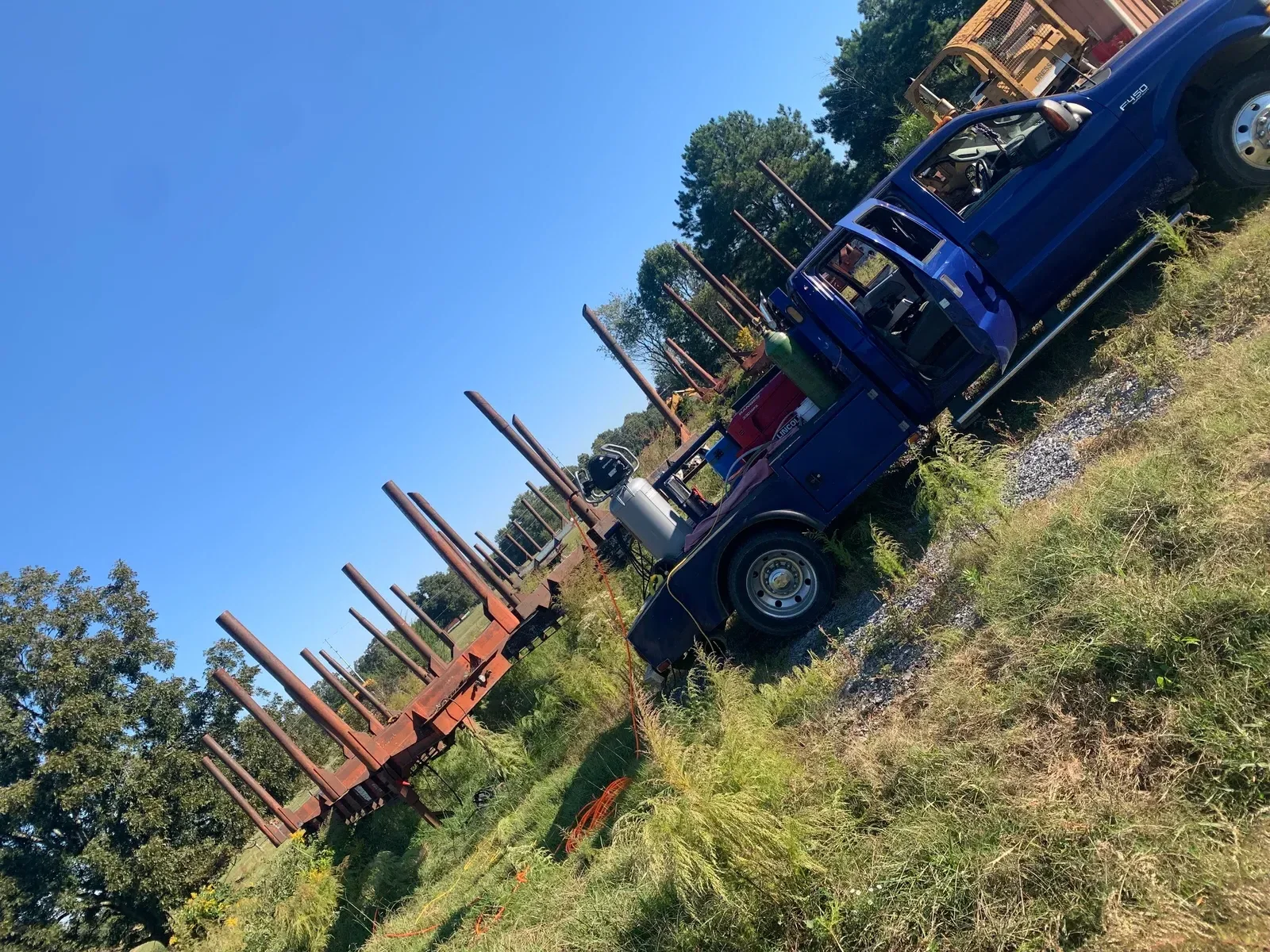 Blue tractor and red farm equipment staged for repair and maintenance work in field setting