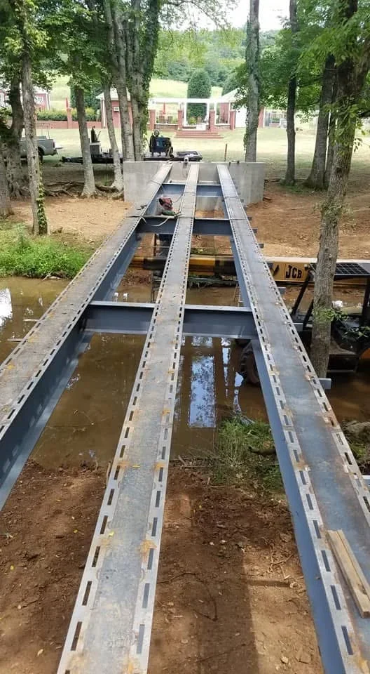 Welded steel channel framework spanning water with reinforced rivet holes and structural supports