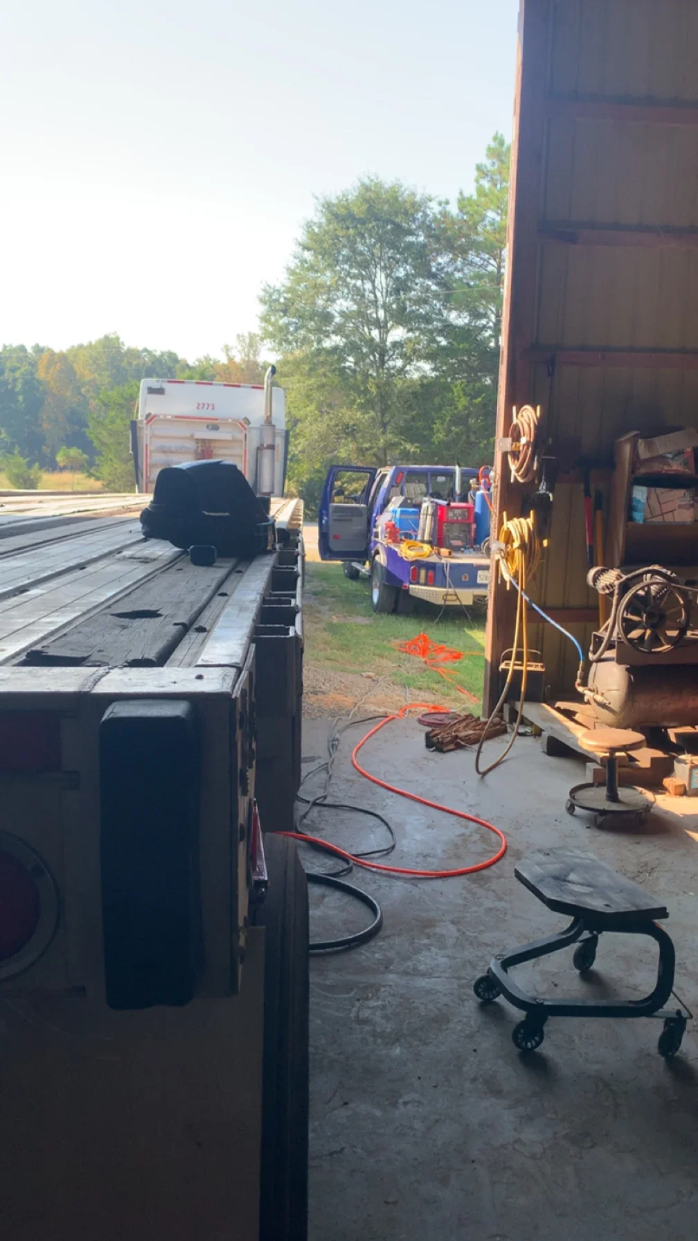 Portable welding setup with red cables and equipment repairing truck bed and trailer frame