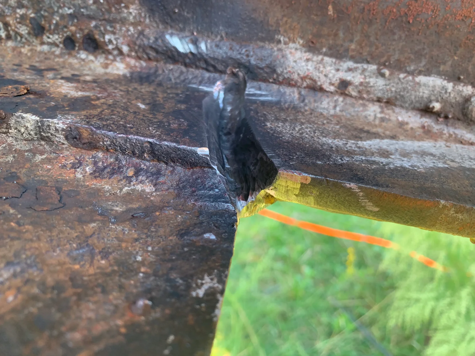 Corroded metal pipe with rust and oxidation, marked with bright tape for repair assessment