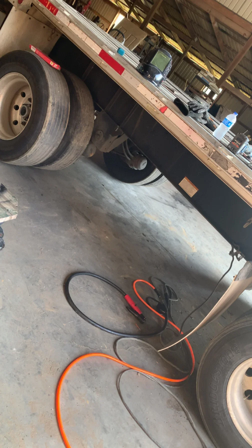 Welded trailer axle assembly with diagnostic testing cables and equipment in workshop