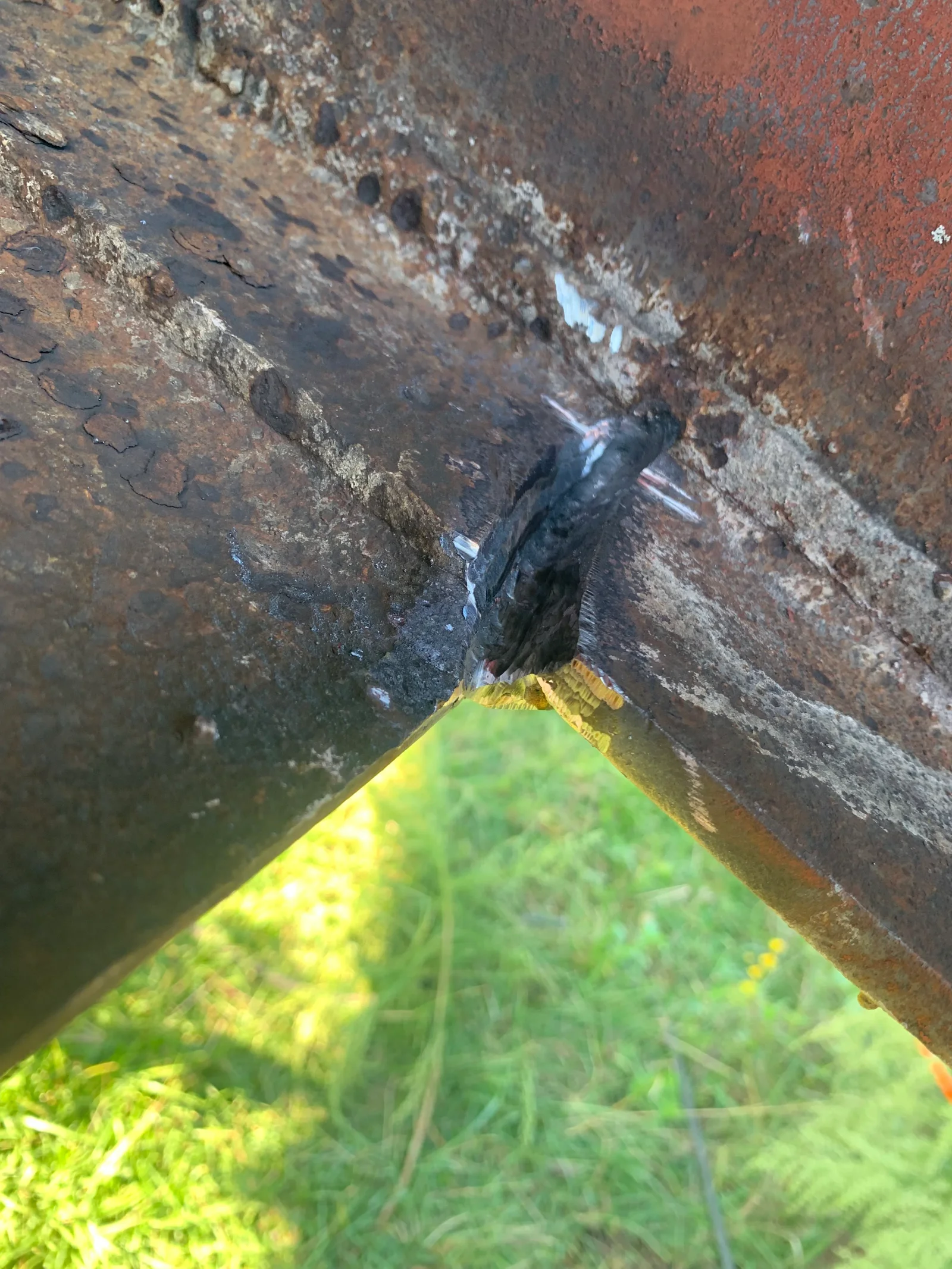 Arc welded steel joint on corroded structural metal with yellow safety marking