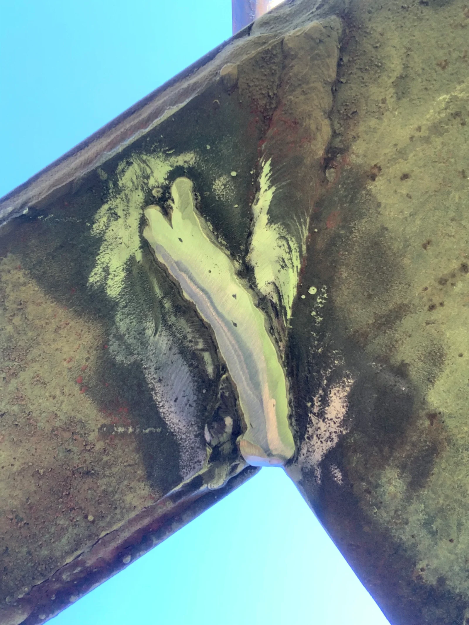 Welded steel beam repair with yellow weld beads on corroded structural member