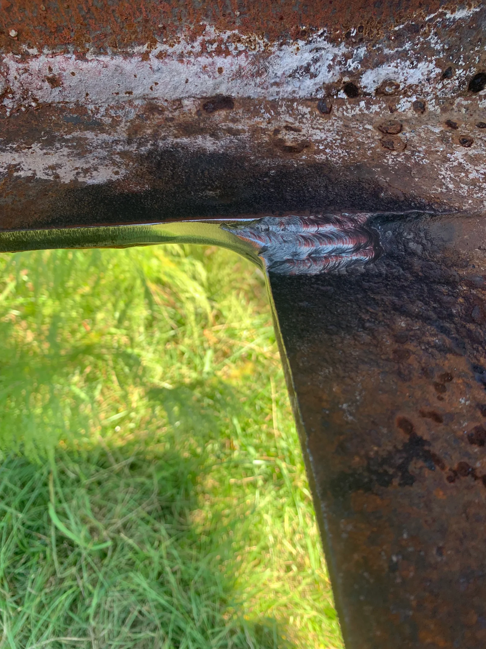 Corroded steel surface with rust removal and metal restoration work in progress
