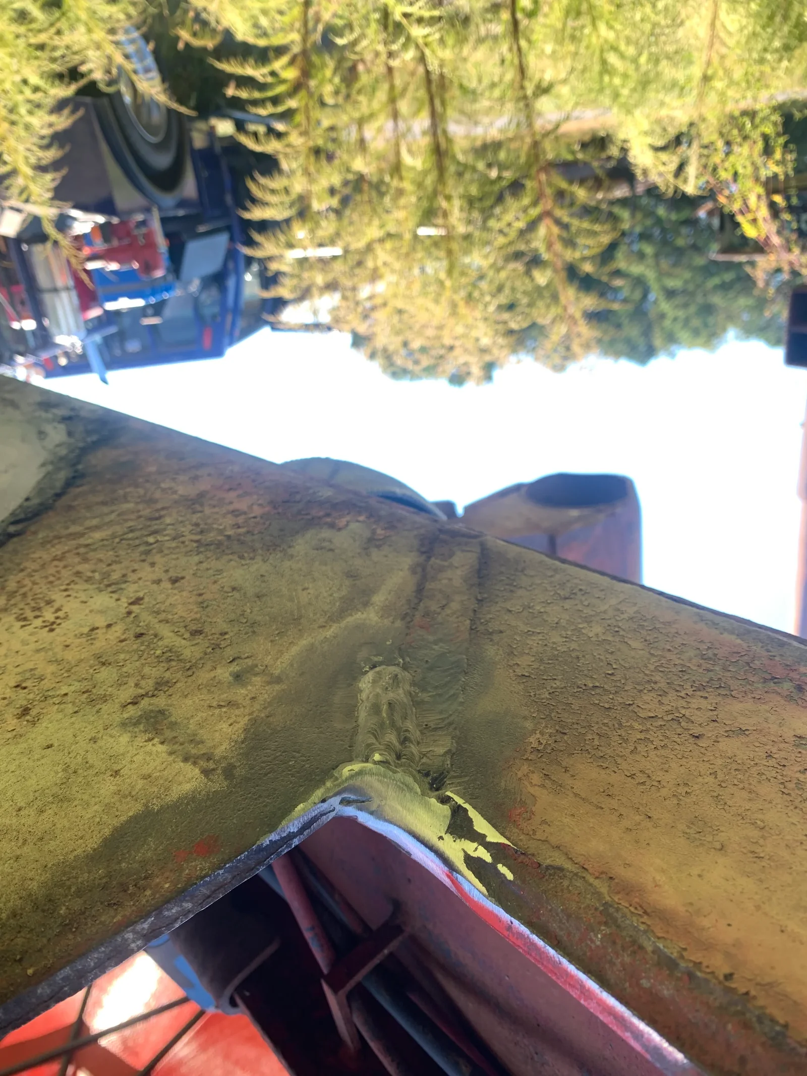 Welded pipe joint with bead on heavy industrial equipment, dirt surface visible