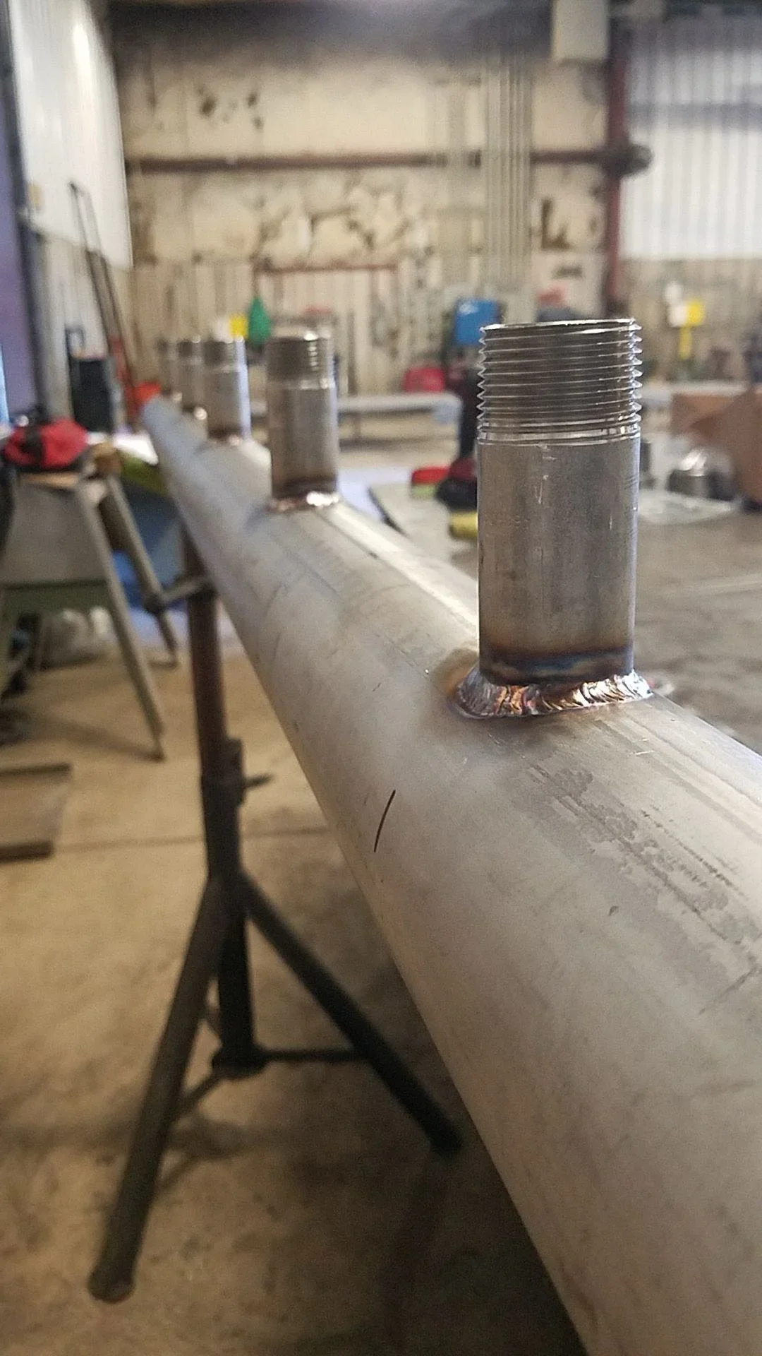 Threaded steel pipe with welded fitting and NPT threads in fabrication workshop