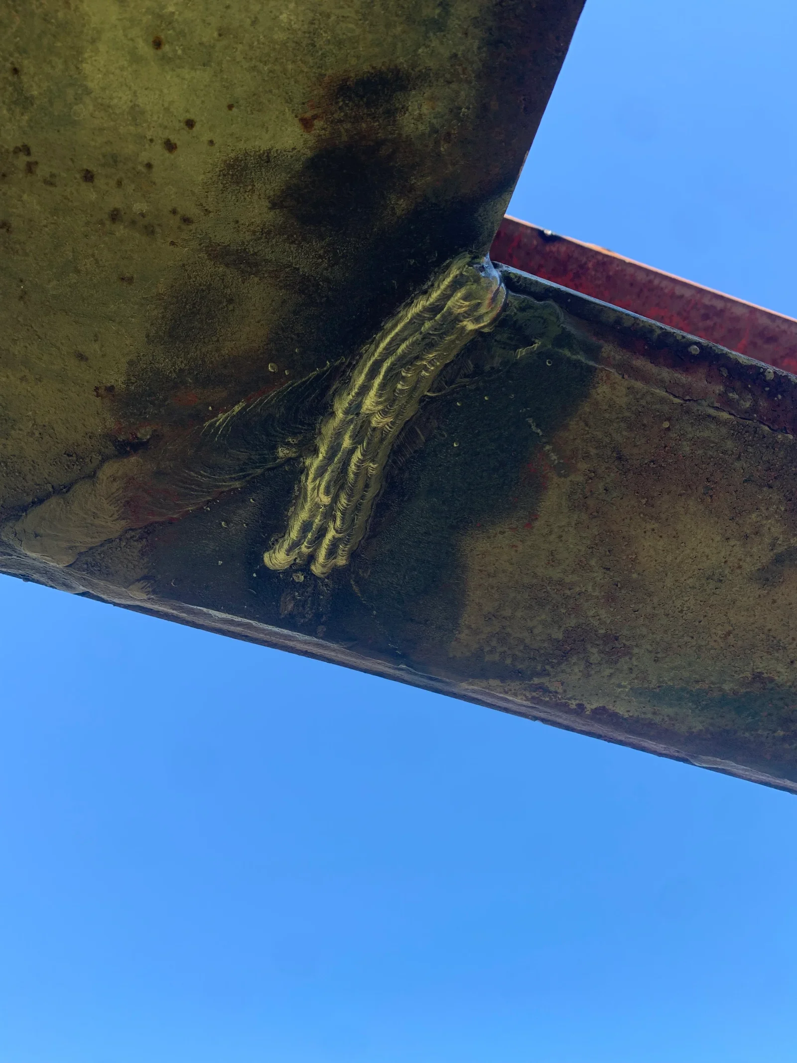 Corroded marine propeller shaft with yellow rope wrapping and rust buildup on vessel hull