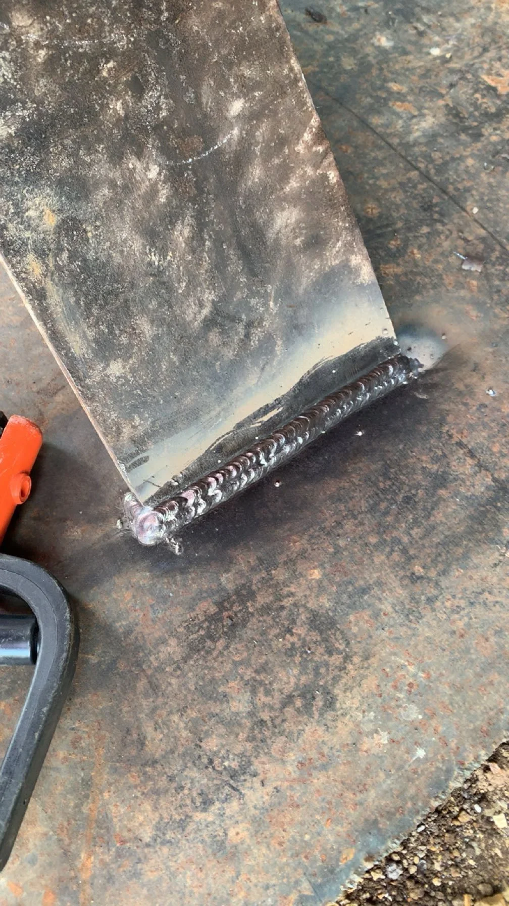 Close-up of welded conveyor roller with metal seam repair on rusted industrial equipment
